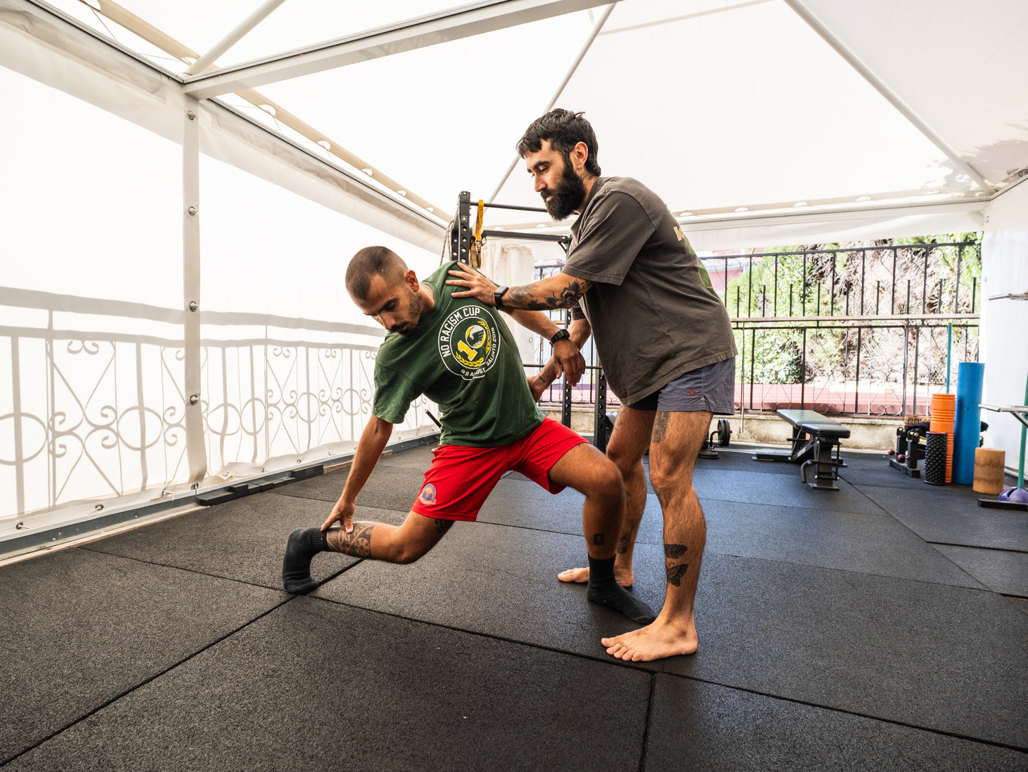 Two men exercising together on a mat in a gym setting